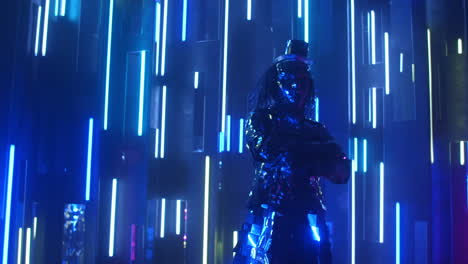 A-steel-man-in-a-sparkling-reflective-suit-shakes-his-head-in-rhythm.-Neon-light-Blue-violet-light.-Show-dancer.